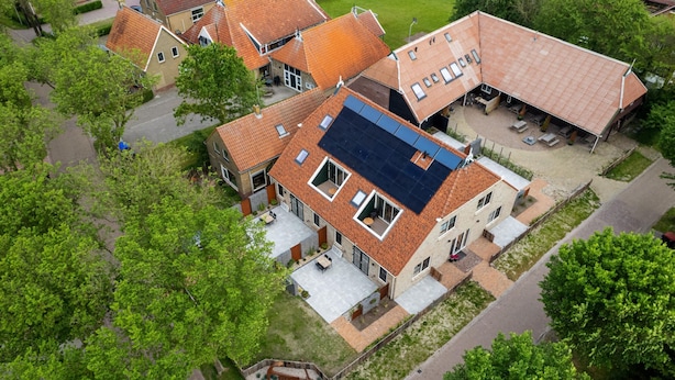 Vista aérea de una zona residencial con casas de tejas rojas y paneles solares.