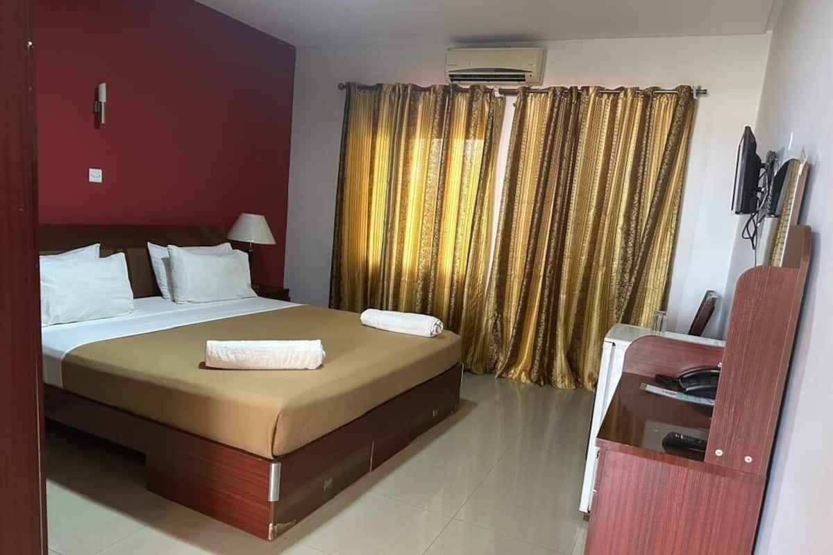 Ein Hotelzimmer mit Bett, Schreibtisch, Klimaanlage und Vorhängen.