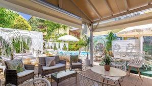 Een terras buiten met rieten meubels, een ronde tafel en parasols.