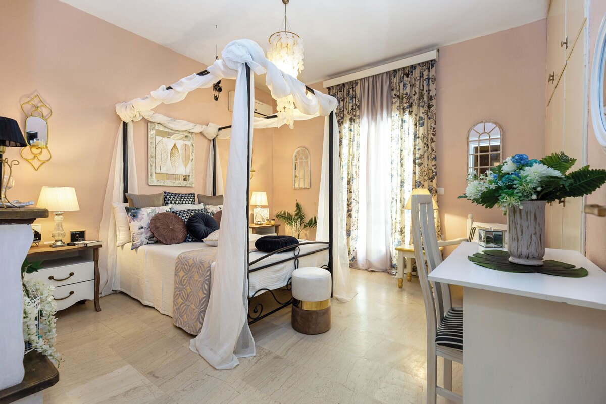 Ein Schlafzimmer mit Himmelsbett, Nachttischen, Schreibtisch und Stuhl.