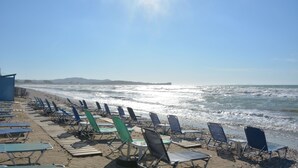 Een strand met rijen ligbedden en een helder uitzicht op de oceaan.