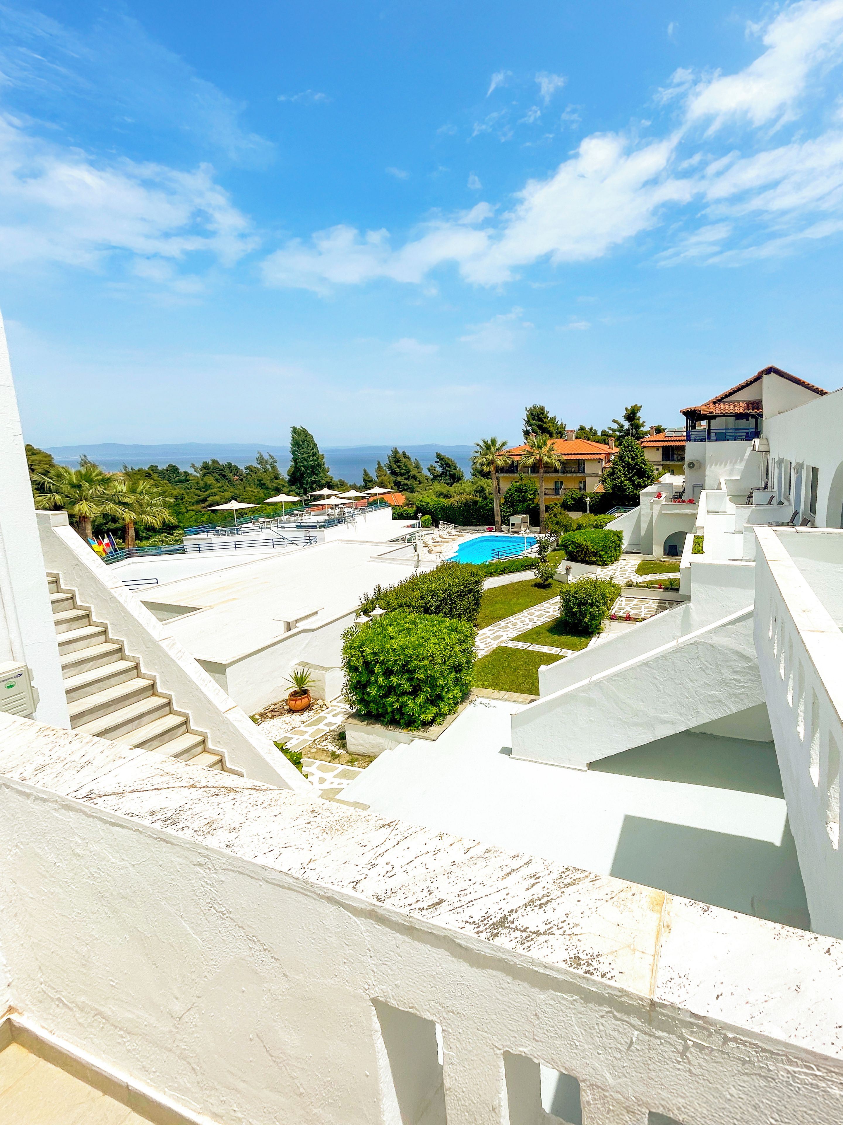 A resort with a pool, a staircase, and a view of the sea.