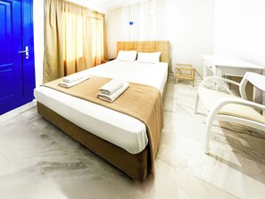 Ett hotellrum med en säng, ett skrivbord och en stol.