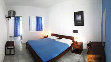 A hotel room with a bed, bedside tables, a desk, a chair, a lamp, a picture on the wall, and a window with curtains.