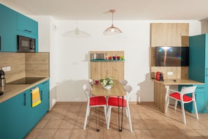 Una cocina moderna con encimera de madera, microondas, lavaplatos, una mesa de comedor con sillas y un televisor montado en la pared.