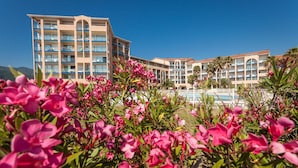 A hotel with multiple balconies, a pool, and a clear blue sky.