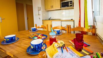 Una mesa de comedor con vajilla azul y roja, un edredón amarillo y materiales de arte.
