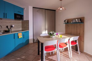 Una cocina moderna con armarios azules, un microondas y una mesa de comedor de madera con sillas blancas.