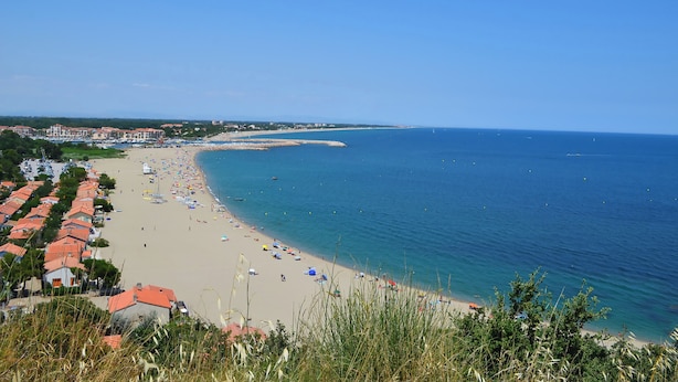 A coastal beach with rows of houses, a sandy shore, and the sea.