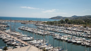 A marina filled with numerous boats docked in calm waters, surrounded by hills and a clear sky.