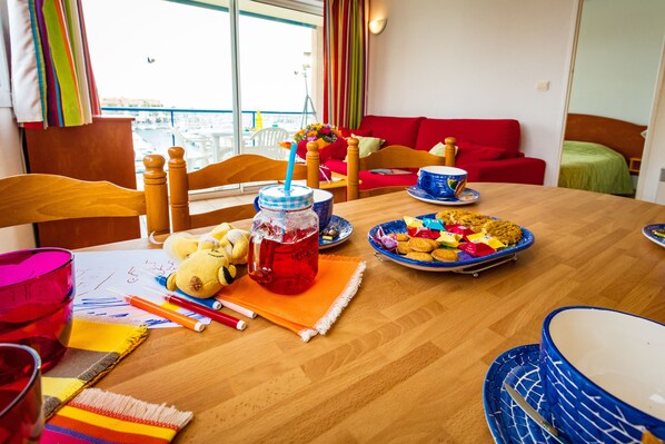 A dining table with a variety of food items, a teddy bear, and a jar with a straw.