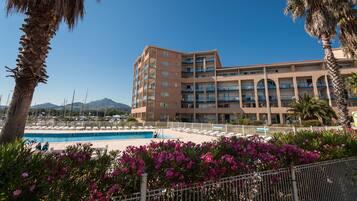 Un hotel con piscina, palmeras y un cielo azul despejado.