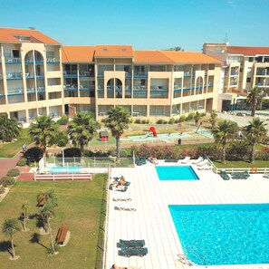 Un hotel con piscina, varios balcones y palmeras.