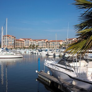 A marina with boats docked, a row of hotel buildings, and a clear sky.