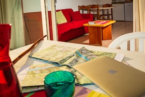 Una habitación con sofá rojo, mesa de madera y una computadora portátil sobre la mesa.