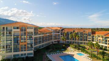 Un hotel con varias plantas, piscina y palmeras.