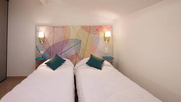 Una habitación con dos camas, un cuadro abstracto de colores y dos lámparas de pared.