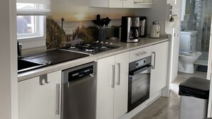 Una cocina moderna con gabinetes blancos, electrodomésticos de acero inoxidable y techo de madera.