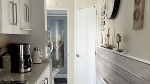 Una cocina moderna con armarios blancos, un cubo de basura negro y piso de madera.