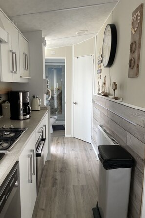 A modern kitchen with white cabinets, a black trash bin, and a wooden floor. - RBR 852 - Beach Resort Kamperland by Interhome (Kamperland)