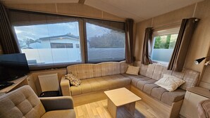 Ein kompaktes Wohnmobil-Interieur mit einer Sitzecke, einem kleinen Tisch, einem Fernseher und einer Heizung.