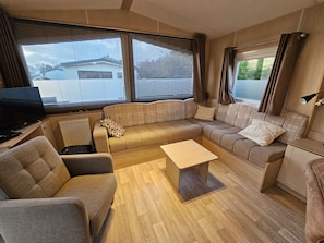 Ein kompaktes Wohnmobil-Interieur mit einer Sitzecke, einem kleinen Tisch, einem Fernseher und einer Heizung.