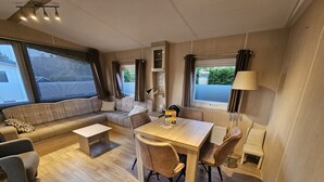Ein gemütlicher Wohnbereich mit Sofa, Esstisch, Stühlen, einer Lampe und einer Heizung.