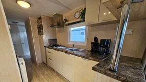 Eine kompakte Küche mit eingebautem Herd, Spüle und Kaffeemaschine.
