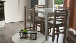 Una cocina compacta con refrigerador, una mesa de comedor con sillas y una pequeña mesa redonda con una planta.