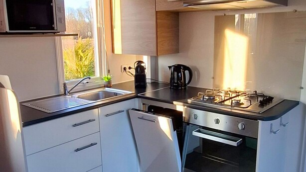 Una cocina compacta equipada con microondas, estufa, horno y lavaplatos.