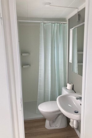 A bathroom with a toilet, sink, and shower curtain. - KD 822 - Vakantiepark Kijkduin by Interhome ('s-Gravenhage)