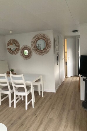 A dining area with a white table and chairs, a wall with decorative mirrors, and a wooden floor. - KD 822 - Vakantiepark Kijkduin by Interhome ('s-Gravenhage)