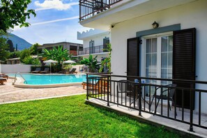 A pool area with a clear view of the pool, lounge chairs, and a small table with chairs. - Aquarius Beach Hotel (Corfu)