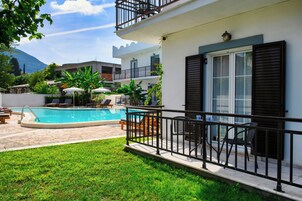 Zona de piscina con vista despejada, sillas de descanso y una pequeña mesa con sillas.