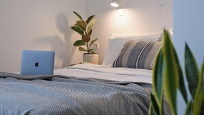 A bedroom with a bed, a laptop on the side, a plant, and a wall-mounted light. - Aquarius Beach Hotel (Corfu)