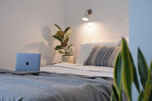 A bedroom with a bed, a laptop on the side, a plant, and a wall-mounted light. - Aquarius Beach Hotel (Corfu)