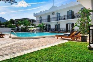 A pool area with lounge chairs, a pool, and a building with balconies.
