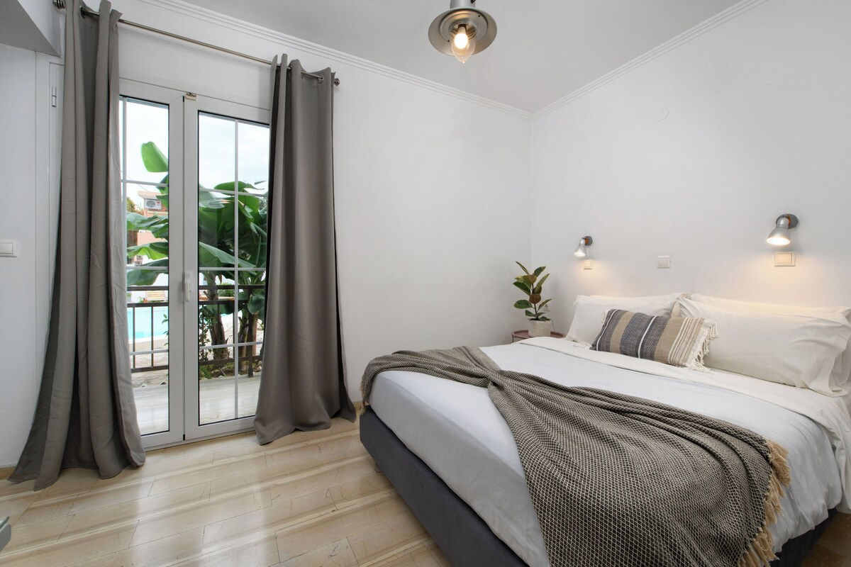 A bedroom with a bed, curtains, a ceiling light, and a view through a sliding door.