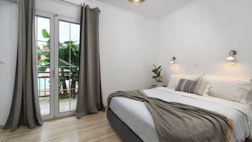 Un dormitorio con cama, cortinas, una lámpara en el techo y vistas a través de un ventanal corredero.