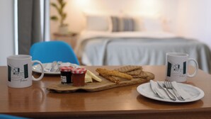 A dining table with a plate of food, two mugs, and a wooden board with condiments. - Aquarius Beach Hotel (Corfu)