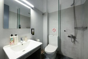 A modern bathroom with a white sink, mirror, and toilet. - Aquarius Beach Hotel (Corfu)