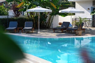Un área de piscina con sillones de descanso y sombrillas.