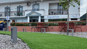 Un hotel llamado 'Aquarius Beach Hotel' con asientos al aire libre y un césped bien cuidado.