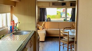 Ein kompaktes Wohnmobil-Interieur mit einer Küchenzeile, einem Essbereich und einer Sitzecke mit Aussicht.
