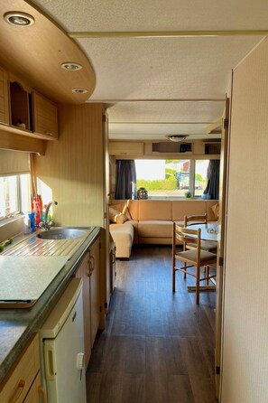 Ein kompaktes Wohnmobil-Interieur mit einer Küchenzeile, einem Essbereich und einer Sitzecke mit Aussicht.