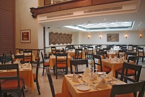 A dining area with multiple tables, chairs, and a high ceiling with skylights.