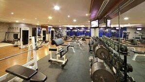 A gym with various exercise equipment, including treadmills, weight machines, and free weights.