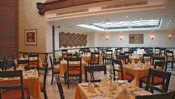 A dining area with multiple tables, chairs, and a high ceiling with skylights.