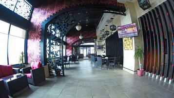 A spacious lobby with a high ceiling, decorative arches, and a seating area with wicker furniture.