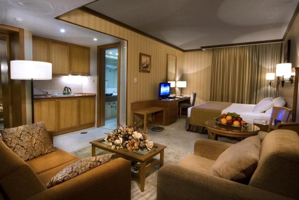 A hotel room with a sofa, a bed, a desk, and a television.